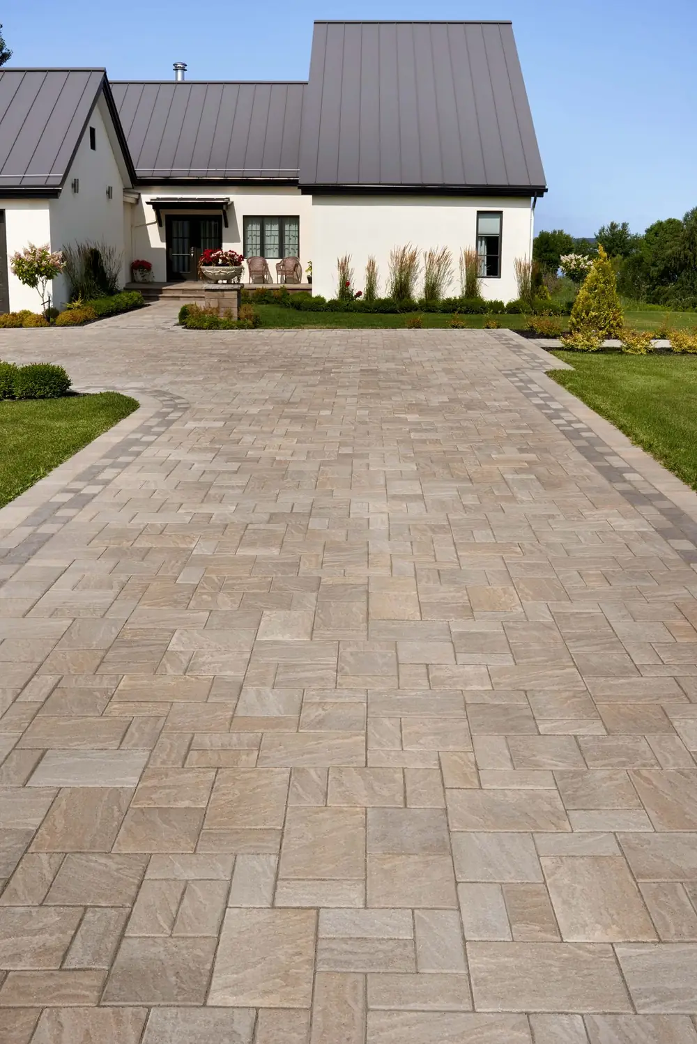 Premium paver driveway curving toward a stone-front house