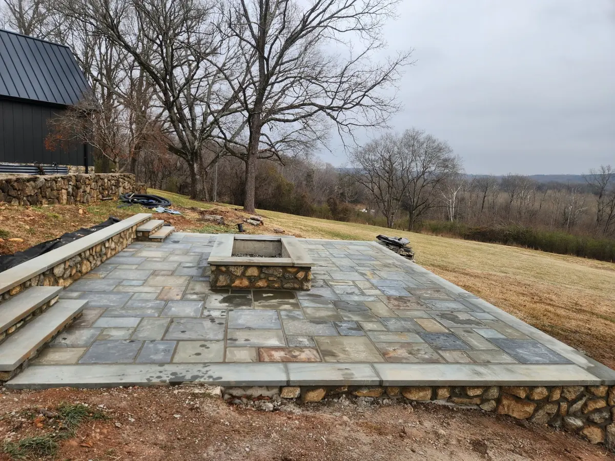 Flagstone patio with a built-in stone fire pit overlooking a rural hillside